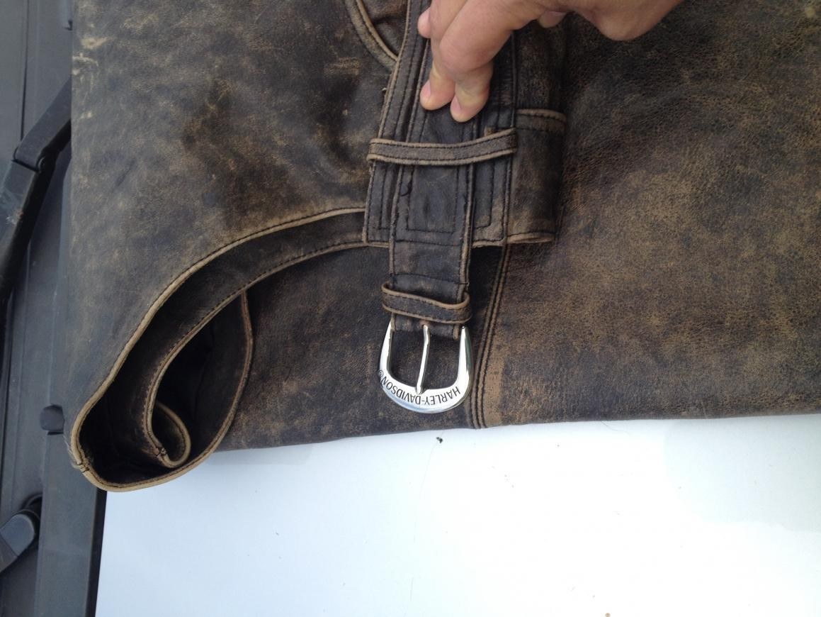 Leather, belt and cut details of chaps designed to be worn over trousers.