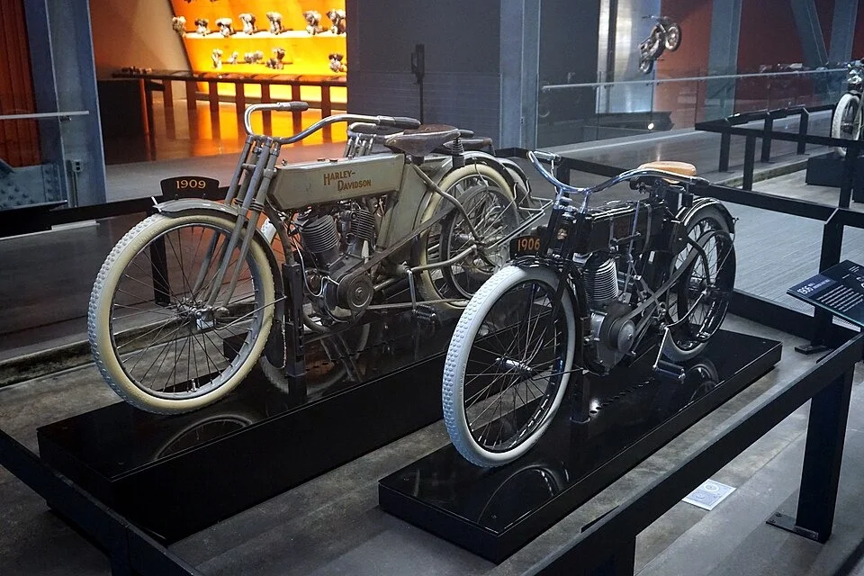 A 1909 Model 5-D displayed alongside a 1906 single-cylinder motorcycle.